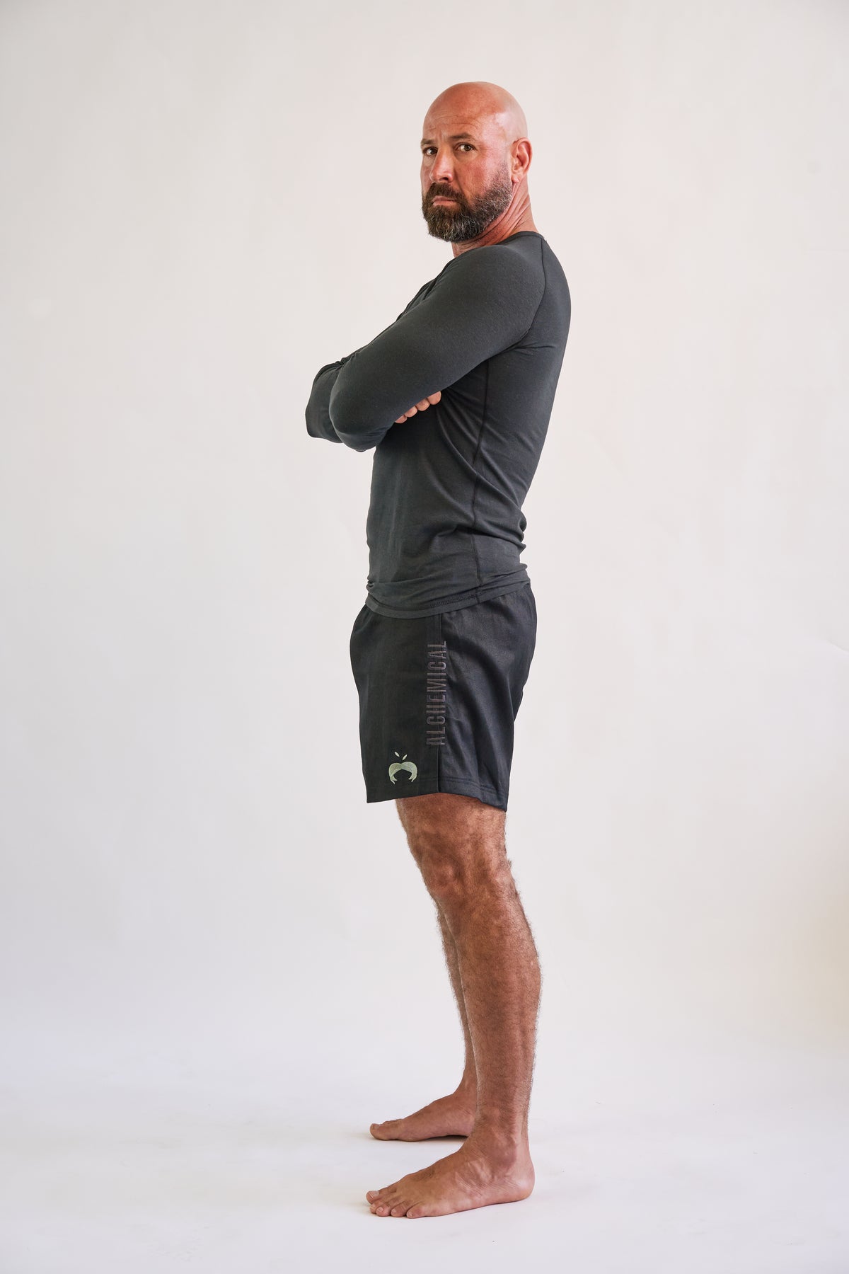 Man wearing a dark long-sleeve shirt and shorts on a white background