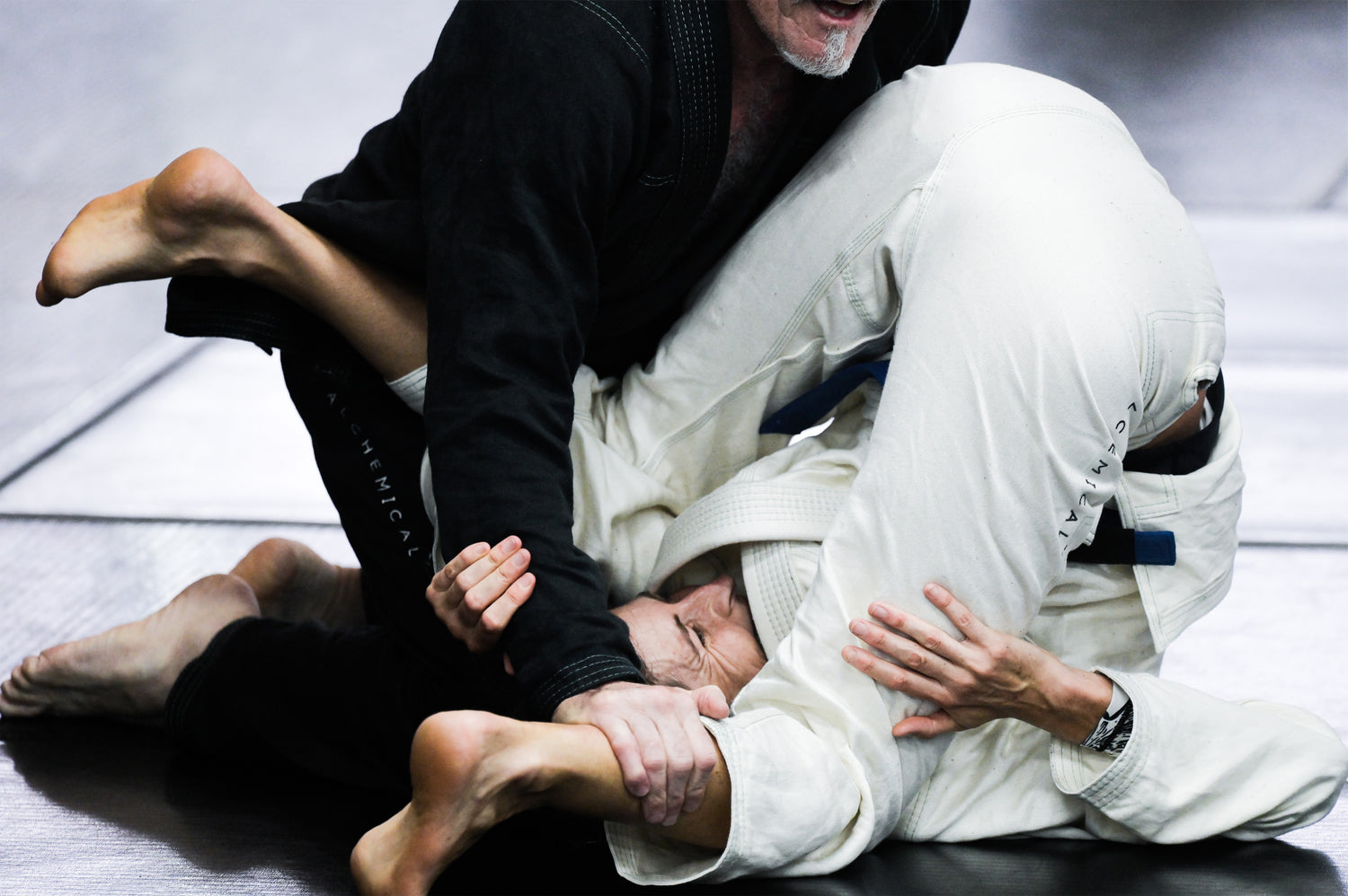 Two men rolling. One appears to be winning. Perhaps he is applying a relaxed approach to his grappling.